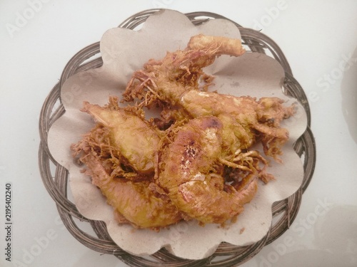 Fotografie Crispy Indonesian deep-fried prawns or udang goreng served on a traditional woven plate lined with paper
