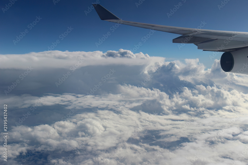 Fototapeta premium Aerial view from an airplane window showing the aircraft wing and engine flying above a sea of thick white clouds
