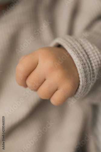 Closeup of a newborn infant baby hand in an outfit