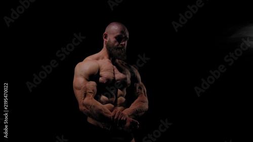A male bodybuilder poses in shorts, showing off his muscles. Close-up of his chest and abs.