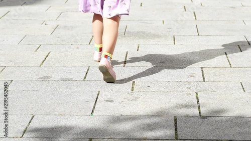 Little girl running outdoors in a park, enjoying a playful and carefree childhood moment. Natural movement and active lifestyle captured in slow motion.