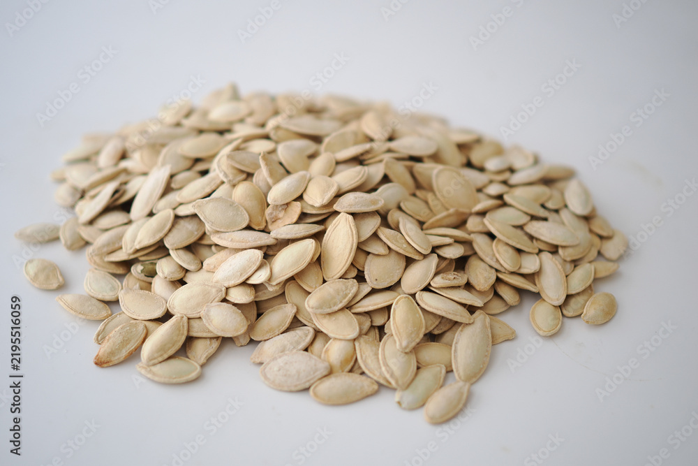 Obraz premium Dry pumpkin seeds placed in a neat pile on a plain surface
