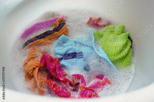 Colorful towels soaking in a basin filled with soapy water for washing