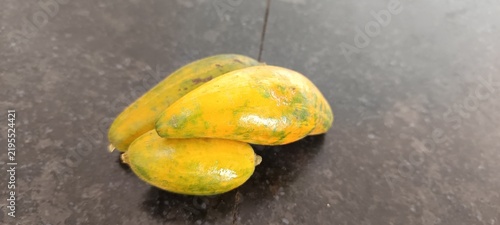 The image appears to show small, unripe or miniature papaya fruits (Carica papaya) transitioning from green to yellow.