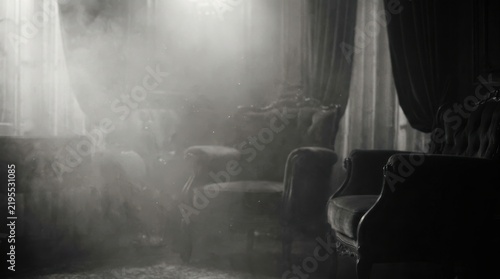 Empty vintage armchairs in a dark room filled with silver fog and light beams