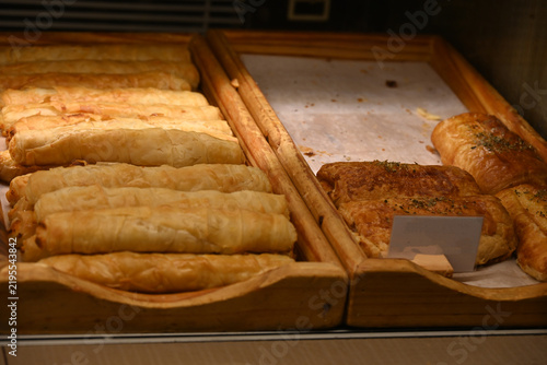 assorted fresh pastries displayed in bakery showcase, assorted fresh pastries, croissants and baked goods displayed in a bakery showcase. variety of savory and sweet pastry products arranged on wooden