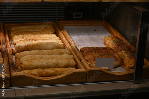 assorted fresh pastries displayed in bakery showcase, assorted fresh pastries, croissants and baked goods displayed in a bakery showcase. variety of savory and sweet pastry products arranged on wooden