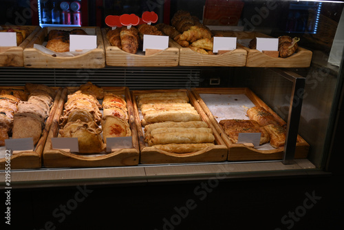assorted fresh pastries displayed in bakery showcase, assorted fresh pastries, croissants and baked goods displayed in a bakery showcase. variety of savory and sweet pastry products arranged on wooden