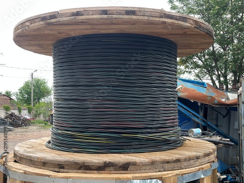 Large coil containing hundreds of meters of thick electrical cable for power distribution and building electrification. Energy infrastructure, electrical installation, power transmission, construction