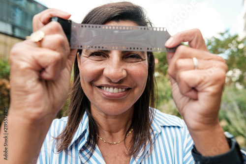 Canvas Print Smiling woman holding film strip appreciating retro photography