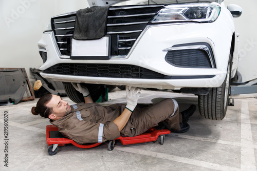 Mechanic working under a car, lying on a creeper