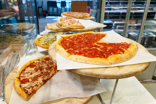 Pizza is a traditional Italian dish consisting of a round yeast-based flatbread baked with toppings. Pizzas in the supermarket on two-tiered stands.