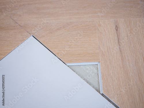 Bild auf Leinwand Light oak look vinyl flooring being precisely cut and fitted next to ceramic tile, showing a detailed floor transition during herringbone installation and home renovation