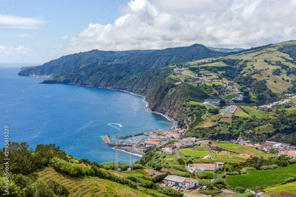 Fototapeta premium Aerial view of Povoacao, a coastal fishing village on Sao Miguel Island in the Azores, Portugal, surrounded by lush volcanic hills and the Atlantic Ocean.