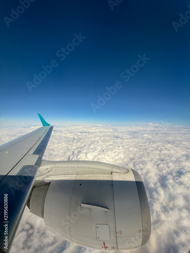 Commercial airplane cruising at high altitude above a beautiful fluffy cloudscape during a flight