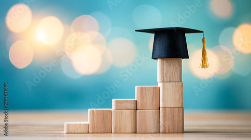 Wooden blocks stacked like a rising bar chart with a graduation cap on top, symbolizing educational growth and success.