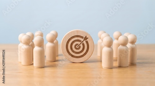 Strategic focus and collaborative teamwork wooden figures surrounding a target representing shared goals and unified effort in a business environment