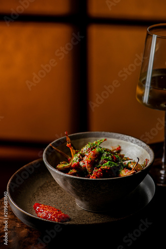 Fotografie Crispy fried okra topped with green herb seasoning and served with chili paste in a dark ceramic bowl