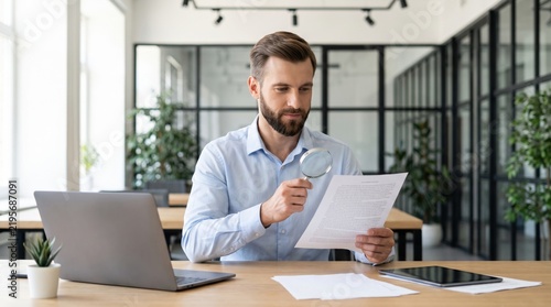 Focused Businessman Examining Documents with Magnifying Glass in Modern Office Setting.