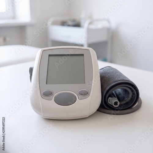 Digital blood pressure monitor device sits on a white clinical table