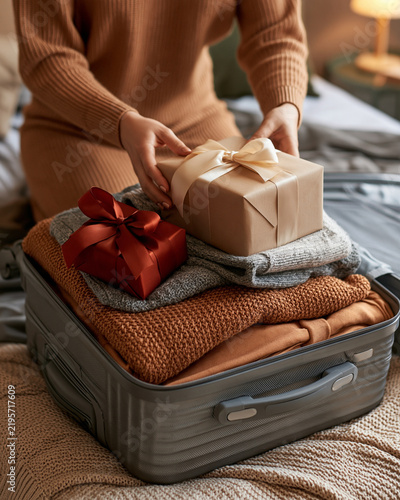 Adult packing winter clothes and gifts for holiday travel