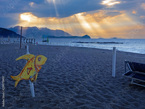 Spiaggia di Spisone con pesce decorativo e raggi di sole al tramonto a Taormina, Sicilia 622