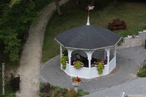 Canvas Print Elegant white gazebo on cobblestone patio in a lush park.