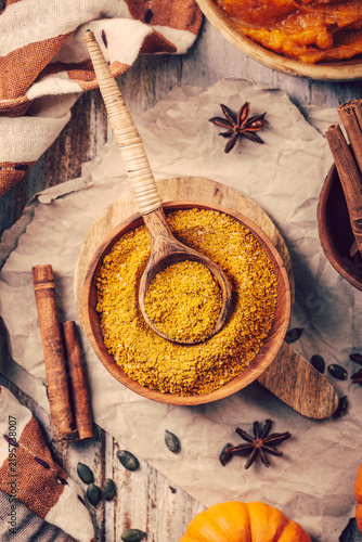 Wooden bowl filled with aromatic pumpkin spice blend on a rustic kitchen table setting