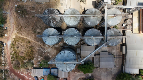 Industrial agricultural complex with large metal grain silos viewed from an aerial perspective