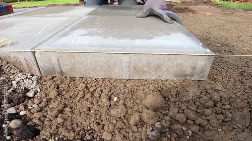 Worker Taps Concrete Paving Slab Into Place With Rubber Mallet