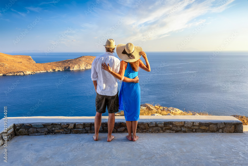 Obraz premium A hugging couple enjoys the elevated view over the ocean during a beautiful summer sunset in the mediterranean, Greece