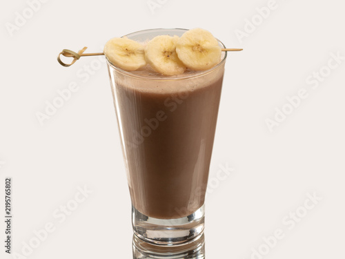 Tall glass of smooth pale beige coconut milk drink with light foam, shot on a plain light background.