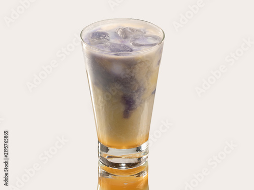 Tall glass of creamy coffee milkshake topped with crushed biscuit crumbs, shot on a light neutral background.