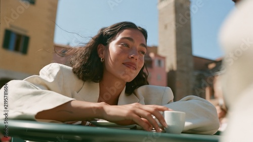 Jeune femme souriante accoudée à une table de café dans une ville italienne
