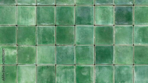 Green square ceramic tiles forming a weathered wall texture