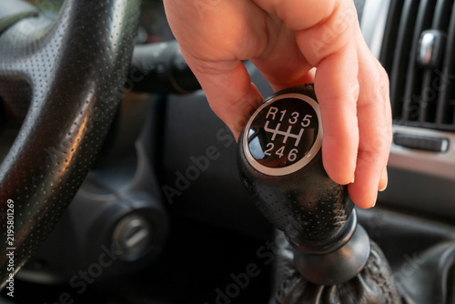 фотографія Hand reaching for a manual gear shift in a car at a parking lot in the late afte
