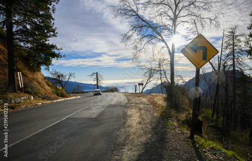 Winding mountain road with a sharp left-turn warning sign. Eleven Range Overlook on Generals Highway. Sequoia National Park. California. USA.