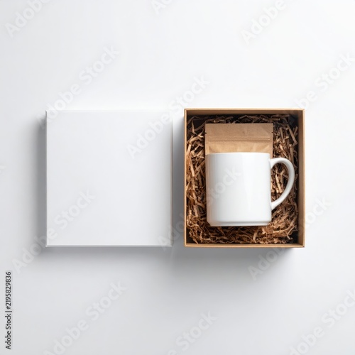 White Ceramic Mug and Blank Card in Brown Gift Box with Shredded Paper on White Background