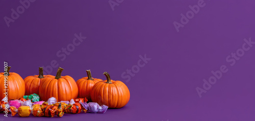 Halloween pumpkins and candy on purple copy space
