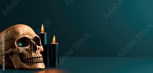 Halloween skull with black candles on dark teal background