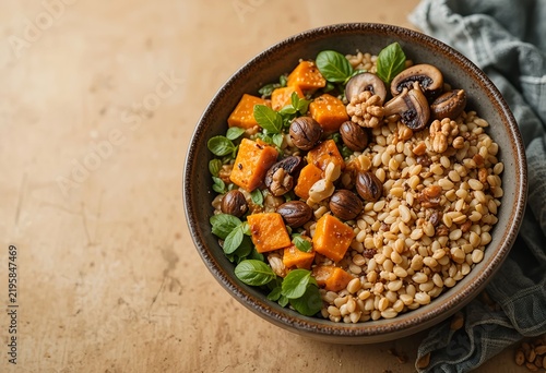 Contemporary autumn grain bowl advertising composition, whole grains topped with roasted pumpkin, sautéed mushrooms, fresh green leaves, toasted walnuts and pumpkin seeds.