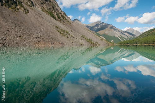 Landscape view of the Lower Shavlinskoye lake with cloudy blue sky reflecting in its water, Russian Federation, the Altai Republic