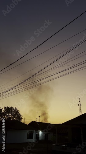 Smoke Rising Above Suburban Houses at Sunset