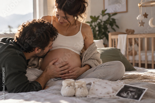 Expectant Couple Bonding With Baby Bump in Cozy Nursery at Home