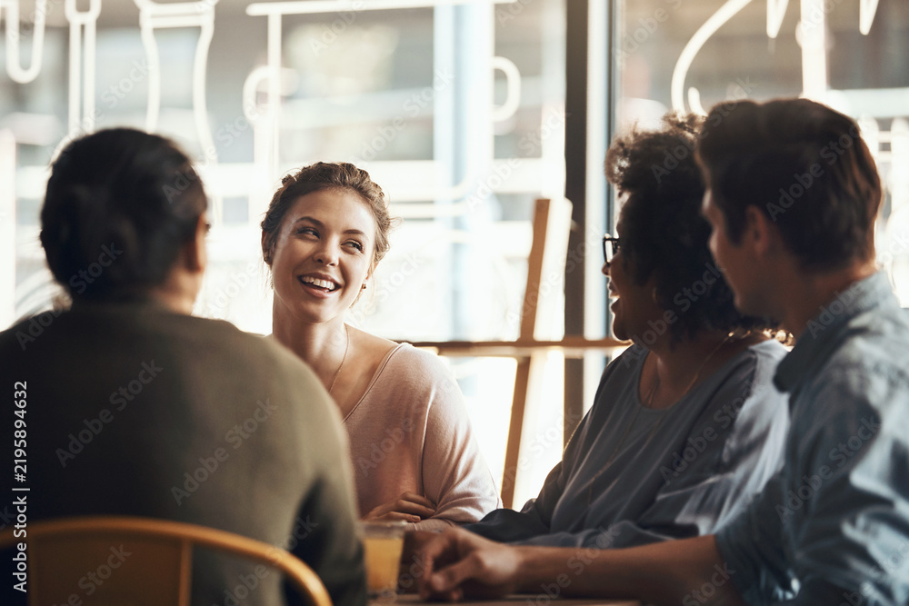 Fototapeta premium Woman, friends and laughing in coffee shop at reunion, bonding or hang out together with smile. Group, communication and happy people at cafe gathering for conversation, funny story or joke for humor