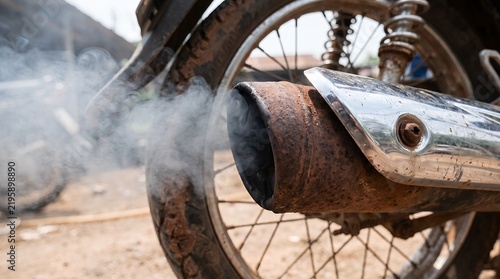 Motorcycle exhaust pipe emitting gray smoke in close-up