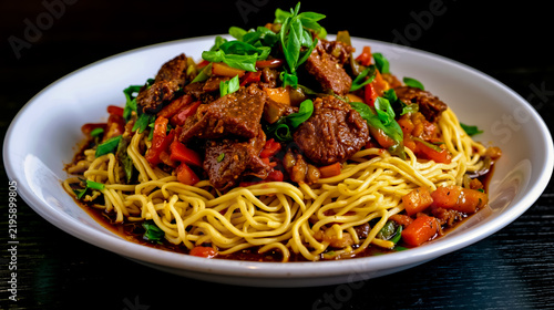 A bowl of beef and broccoli stir fry with noodles and green onions