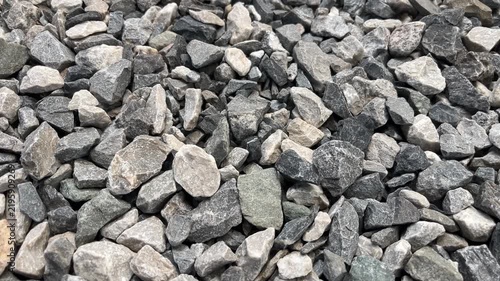 Crushed Stone Background: A detailed, close-up view of a pile of gray and tan crushed stone, showing the rough texture and varied shapes of the rocks, perfect for construction or industrial themes.