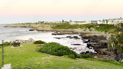 Vibrant moonset behind houses in Hermanus with view over ocean and rocky shore