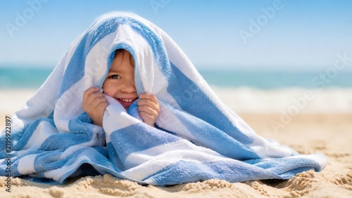 Smiling child wrapped in towel on sunny beach